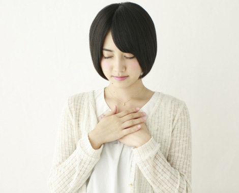 痛む胸を押さえる女性の写真